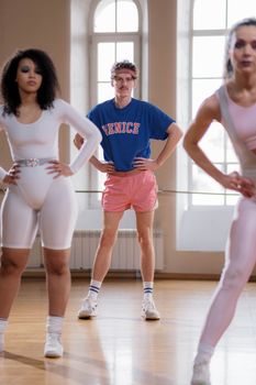 Energetic group exercise class with diverse participants in a bright indoor gym.