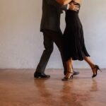Elegant couple performing tango dance on concrete floor, showcasing grace and poise.