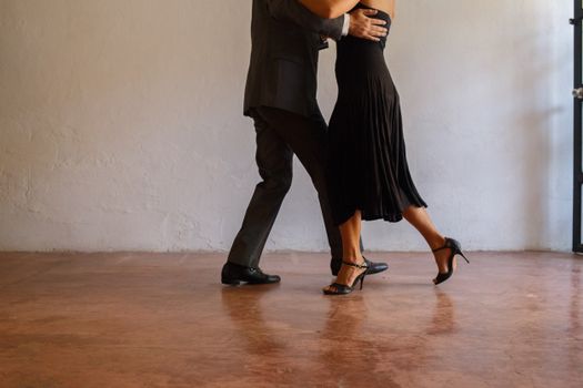 Elegant couple performing tango dance on concrete floor, showcasing grace and poise.